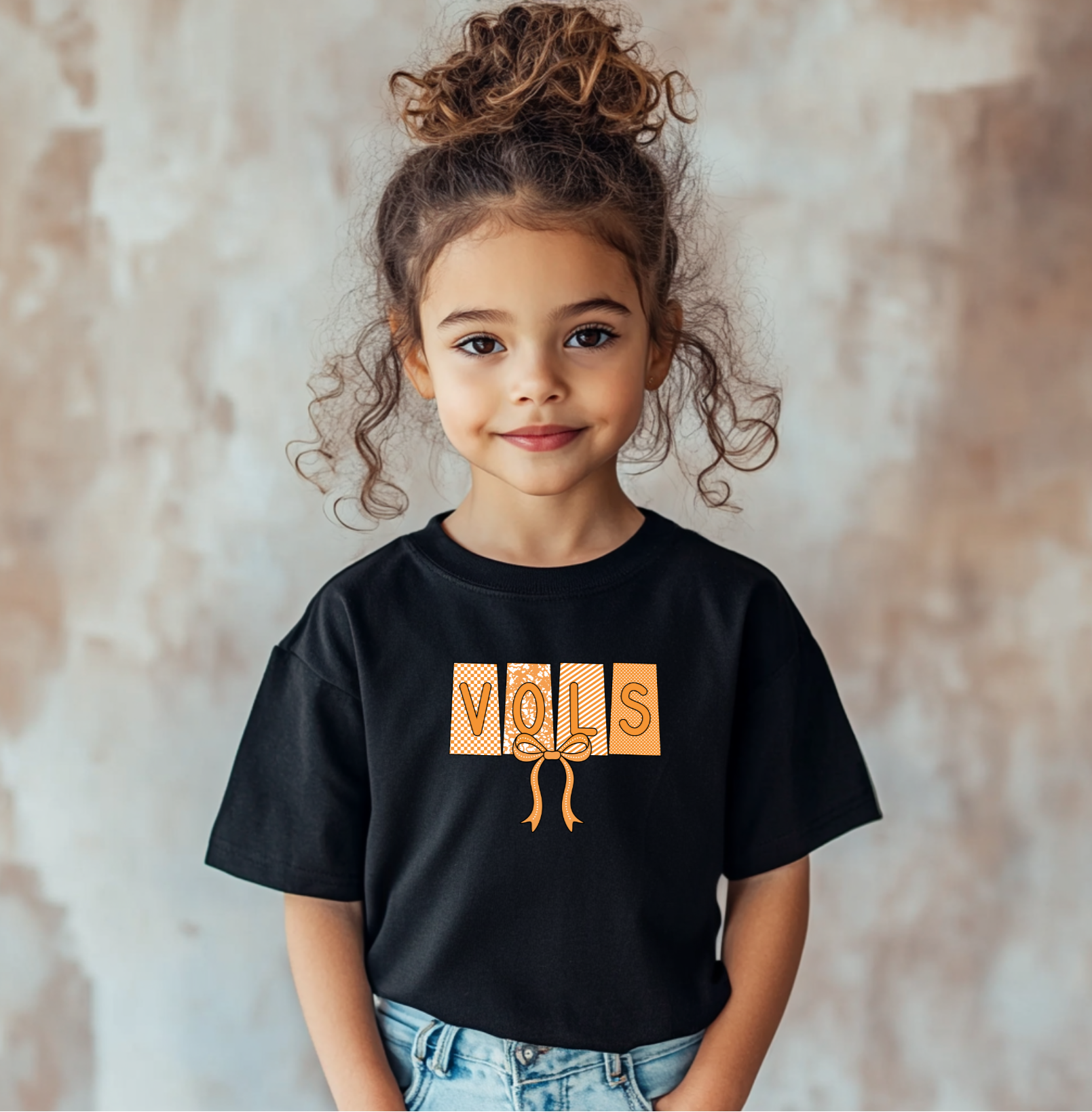 Child wearing a black t-shirt with 'VOLS' design against a neutral background