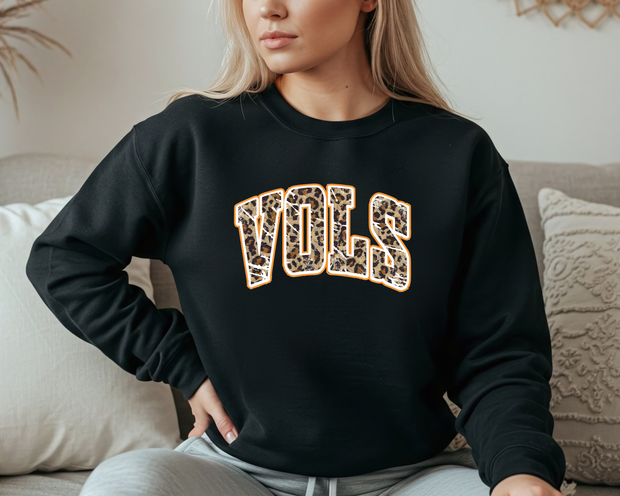 Adult gray sweatshirt featuring a bold leopard print “VOLS” design outlined in orange, displayed flat lay style with jeans and sneakers. Perfect for Tennessee game days and cozy fall weekends.
