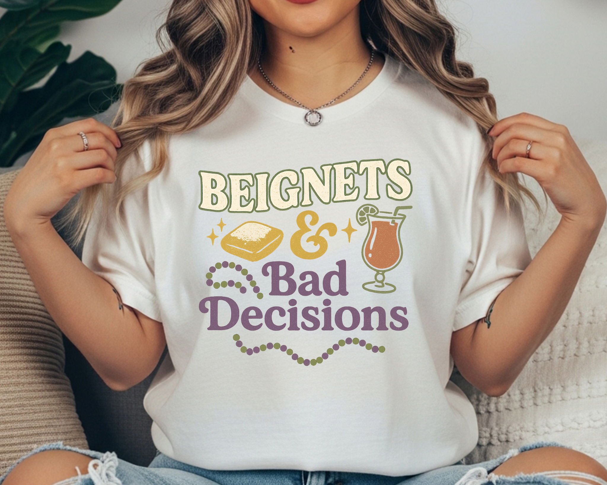 white Comfort Colors tee with Mardi Gras design featuring beignet, cocktail, and text reading “Beignets & Bad Decisions” in purple, gold, and green.