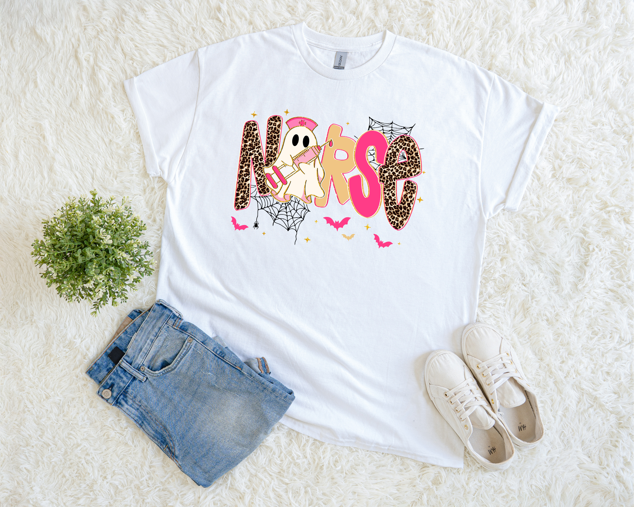white Halloween t-shirt with a playful “NURSE” design featuring leopard print letters, a ghost nurse, spiderwebs, and bats.